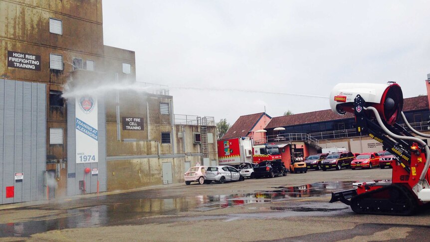 A fire fighting robot sprays a jet of water onto a fire in a car park.