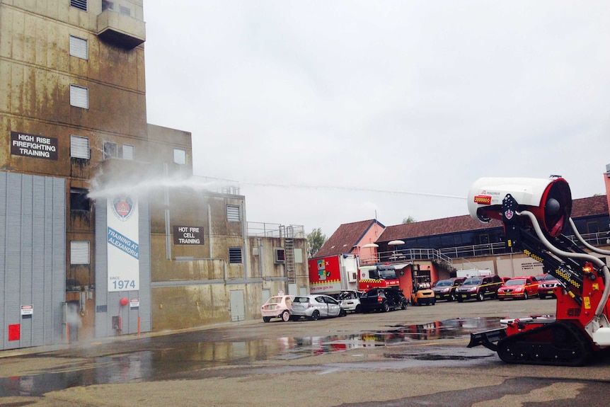 A fire fighting robot sprays a jet of water onto a fire in a car park.