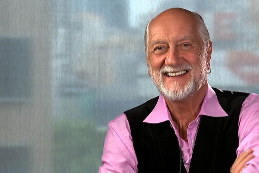 Mick Fleetwood wears a pink shirt and black vest.