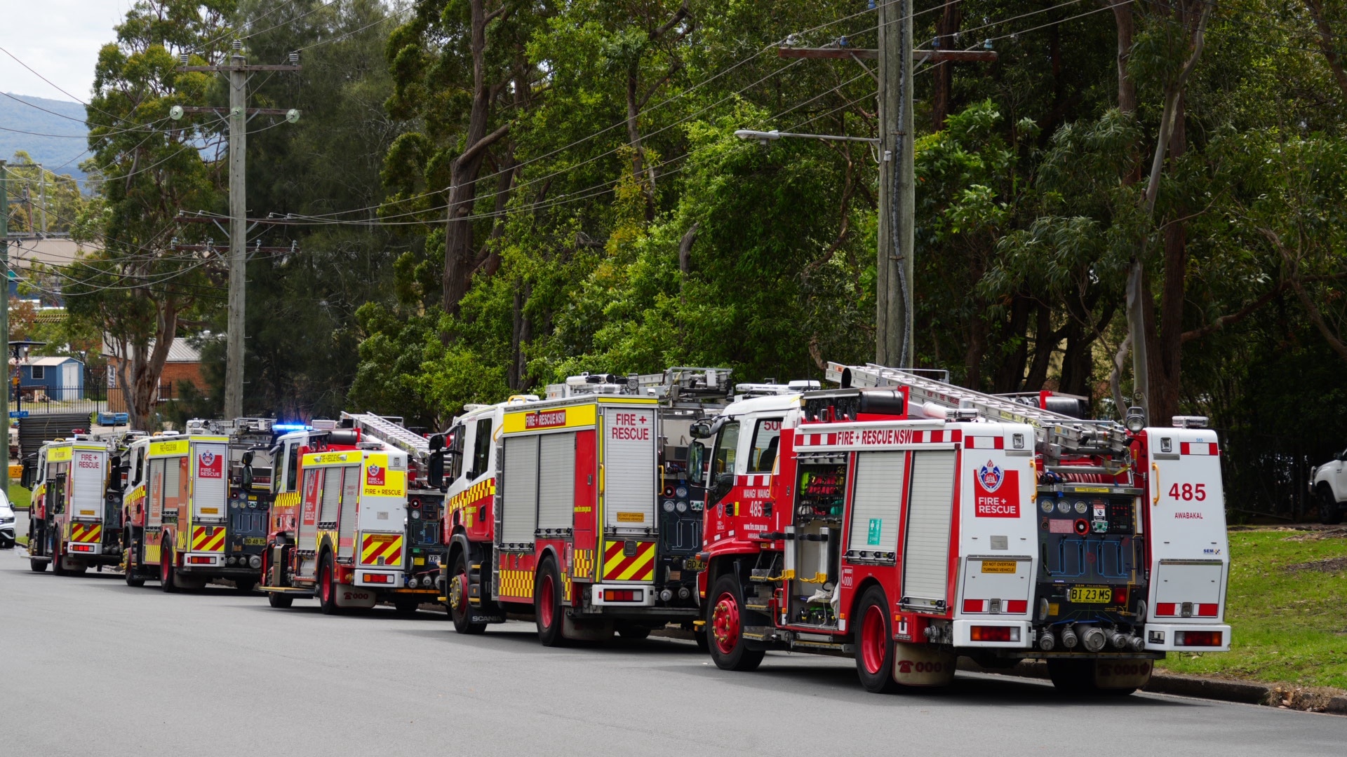 Five fire trucks parked in a row on a street.