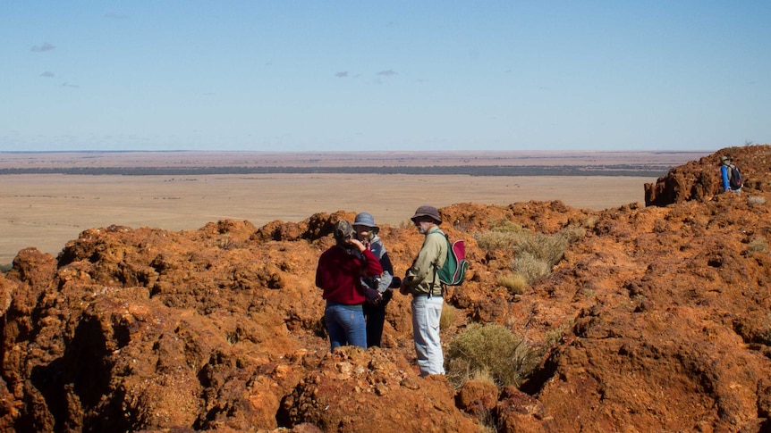 group of people on rocky outcrop with vast open plains in front of them