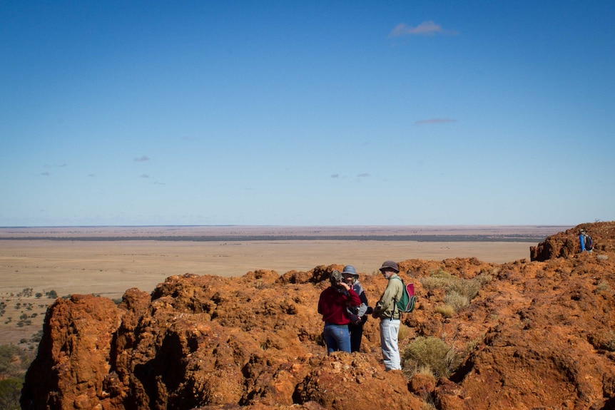 group of people on rocky outcrop with vast open plains in front of them