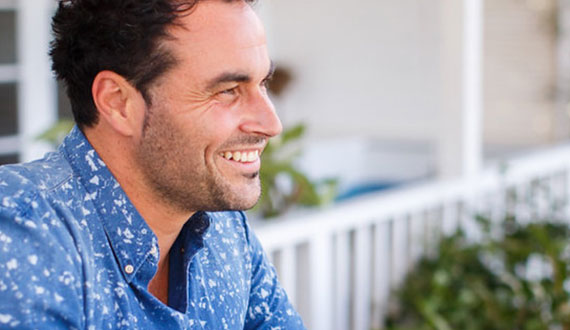 Miguel Maestre wears a blue and white shirt, smiling in the distance.