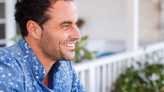 Miguel Maestre wears a blue and white shirt, smiling in the distance.