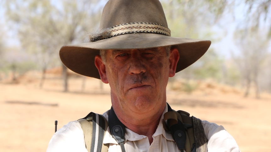 A portrait of Alan Davey wearing an akubra-style hat, standing in the bush.