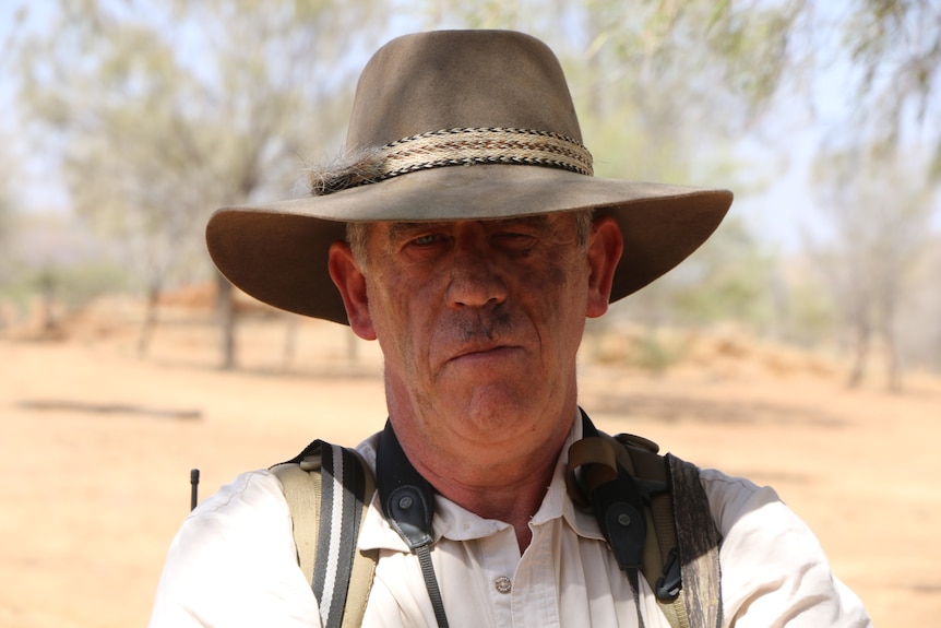 A portrait of Alan Davey wearing an akubra-style hat, standing in the bush.