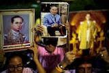 Well-wishers hold pictures of Thailand's King Bhumibol Adulyadej.
