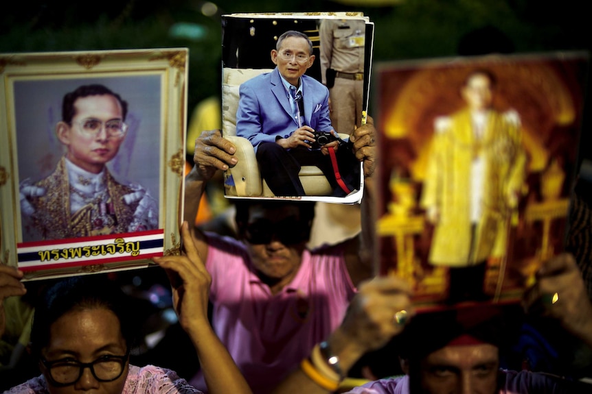 Well-wishers hold pictures of Thailand's King Bhumibol Adulyadej.