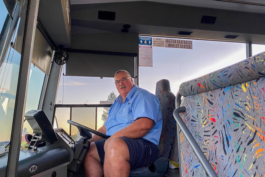 a man sits in the drivers seat of a bus
