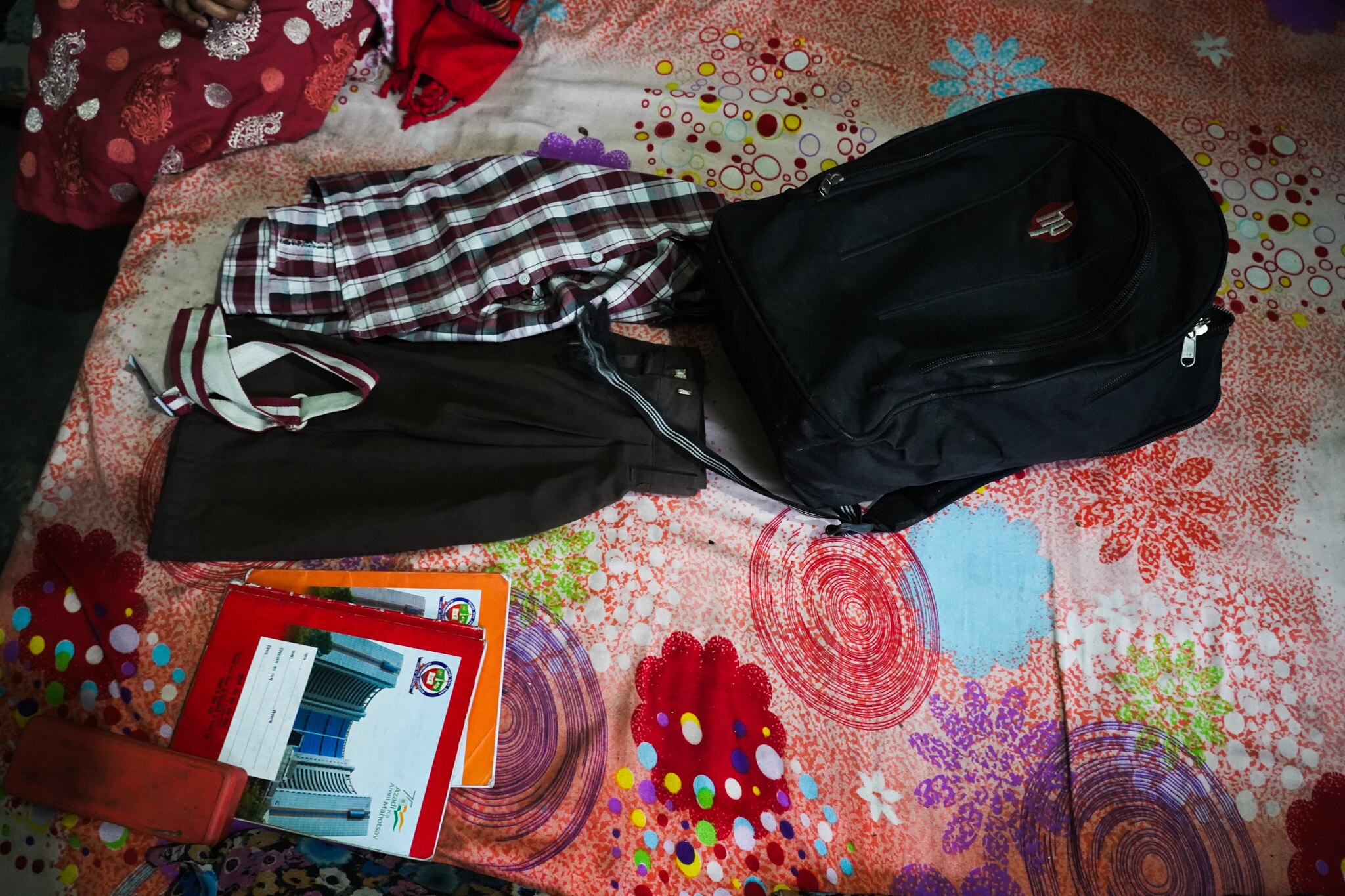 A bag and clothes sit on a bedspread.