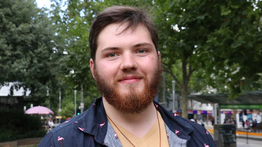 A man smiling to camera in an outdoor area in Melbourne.