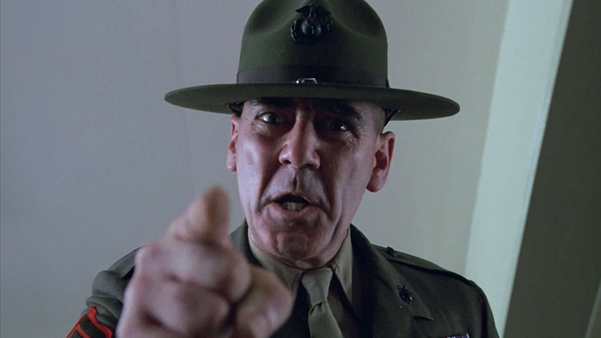 Still from Full Metal Jacket showing close view of just the Gunny's shouting face and a finger pointing towards the camera