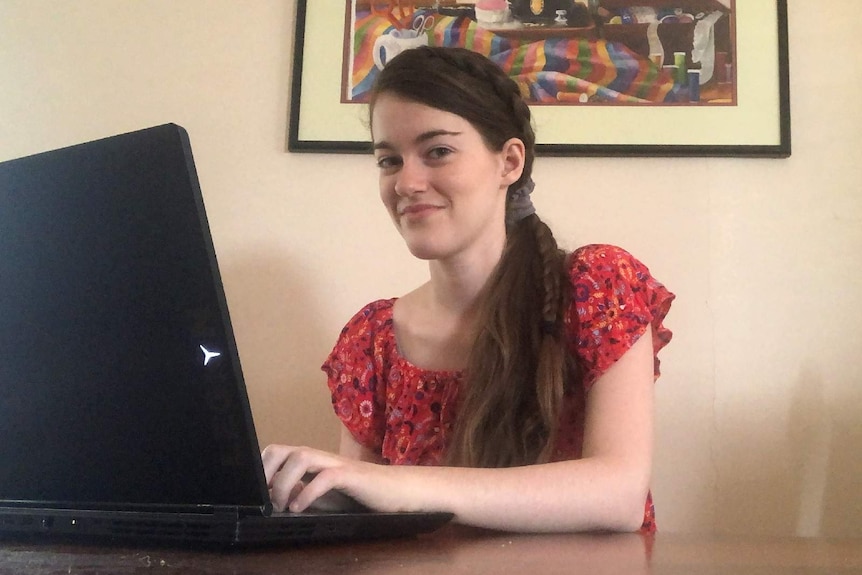 A young woman typing on a laptop at a table