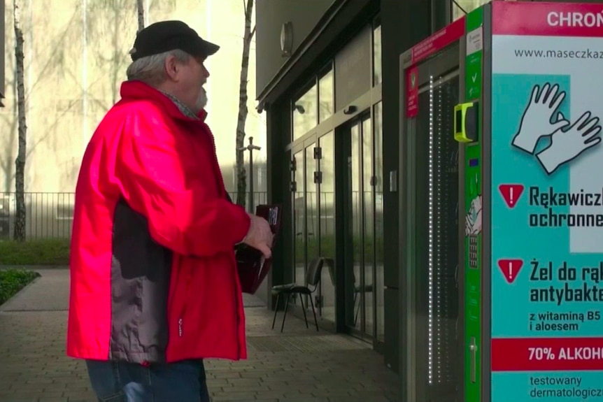 A man in a red jacket stands in front of a vending machine decorated with health guideline infographics