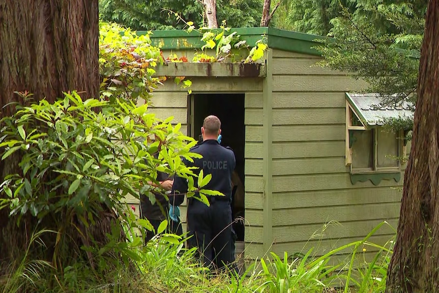 police inspecting a shed in the grassy mountains