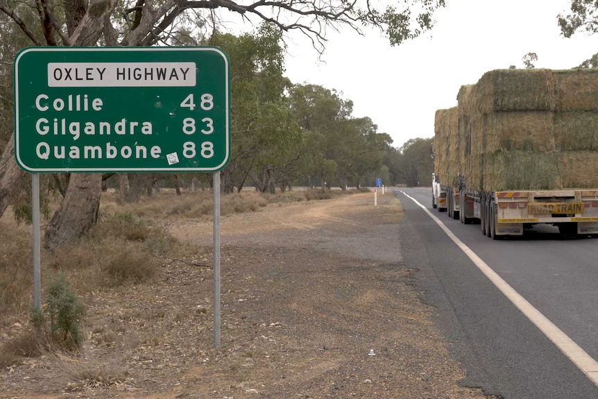 A truckload of hay passing a sign marked 'Oxley Highway'