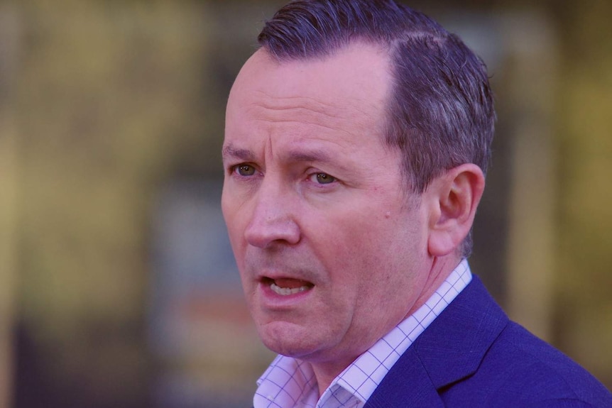 WA Premier Mark McGowan in a shirt and jacket speaking in front of a blurred background.