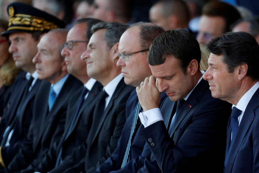 Emmanuel Macron wipes his eye as he sits next to Nice's Mayor, Prince Albert II of Monaco and former French presidents.