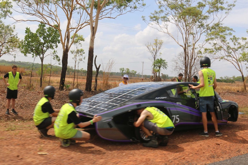 Solar teams working on faulty car on the side of the road