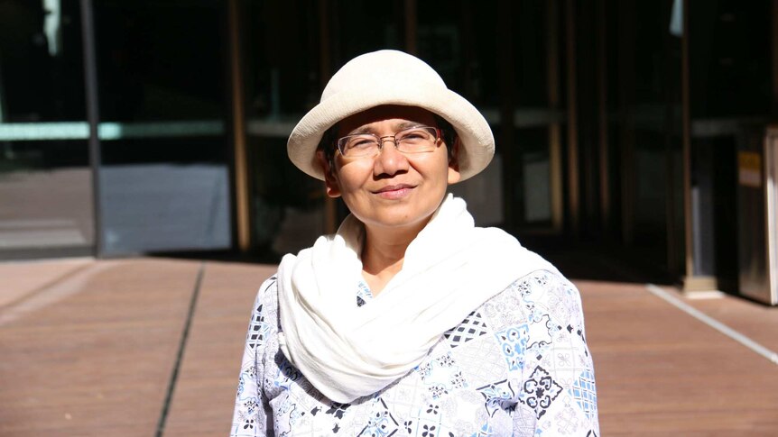 Researcher Zainil Zainuddin, wearing a hat and glasses, stands in the sun.