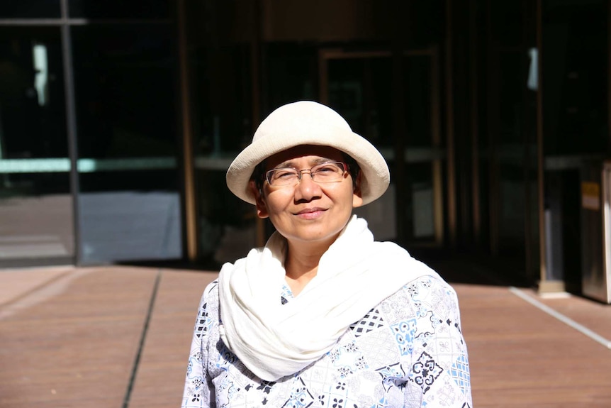 Researcher Zainil Zainuddin, wearing a hat and glasses, stands in the sun.