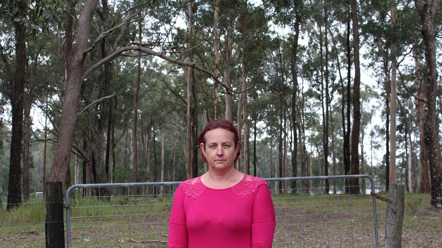 Woombah resident Emma Mills stands on the boundary between her home and to the Woombah Woods Caravan Park.