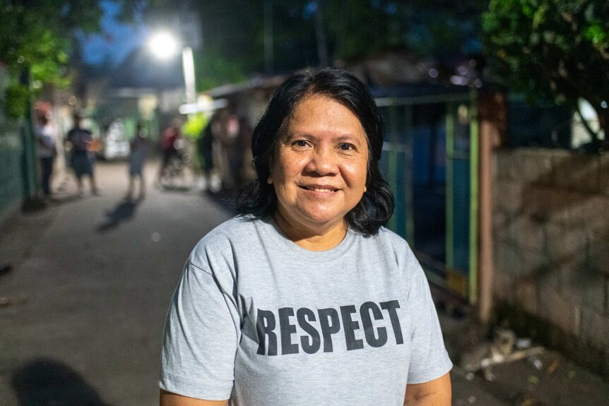 A smiling middle-aged woman in a grey shirt which says "Respect"