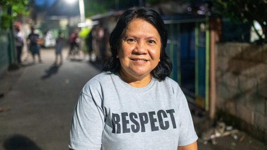 A smiling middle-aged woman in a grey shirt which says "Respect"