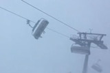 Ski lifts swing side to side, almost horizontally, amid heavy snow.