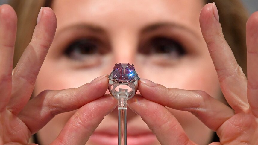 A Christie's jewellery specialist shows the scale of the ring.