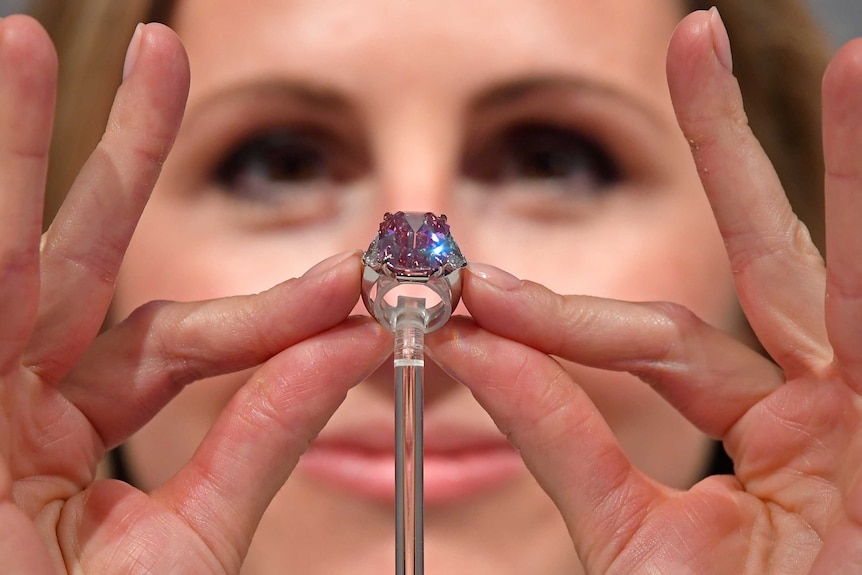 A Christie's jewellery specialist shows the scale of the ring.