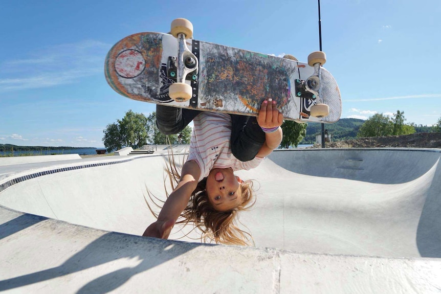 Sky Brown holds herself upside down on a skateboard.