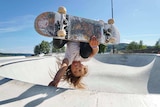 Sky Brown holds herself upside down on a skateboard.