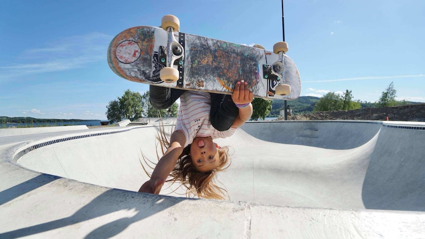 Sky Brown holds herself upside down on a skateboard.