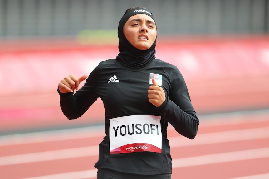  A female Afghanistan athlete stands on the Olympic track in Tokyo after competing in the women's 100m. 