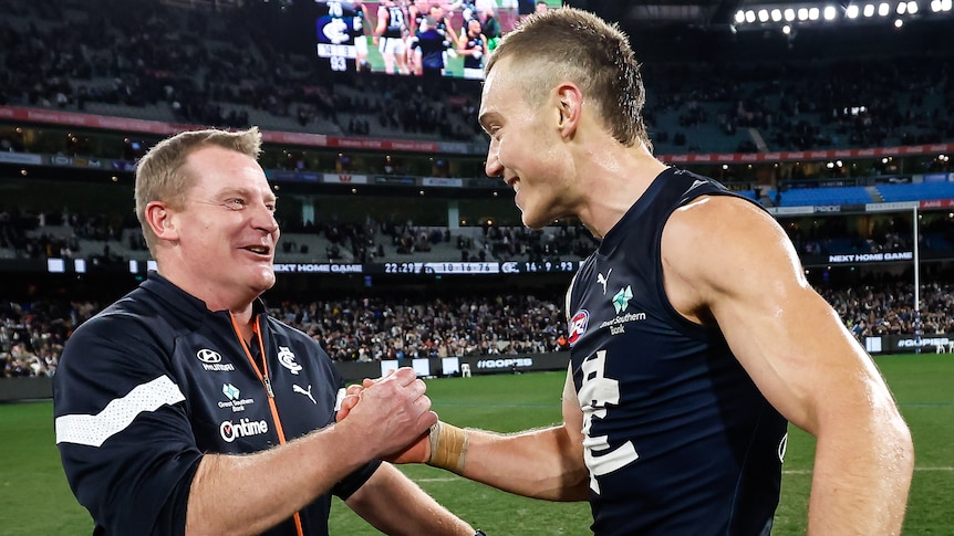 Michael Voss shakes hands with Patrick Cripps on the MCG playing surface after Carlton defeated Collingwood.