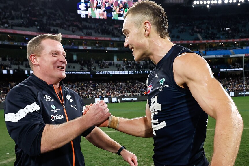 Michael Voss shakes hands with Patrick Cripps on the MCG playing surface after Carlton defeated Collingwood.