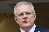 Scott Morrison, with an Australian flag pin on his suit, looks into the distance