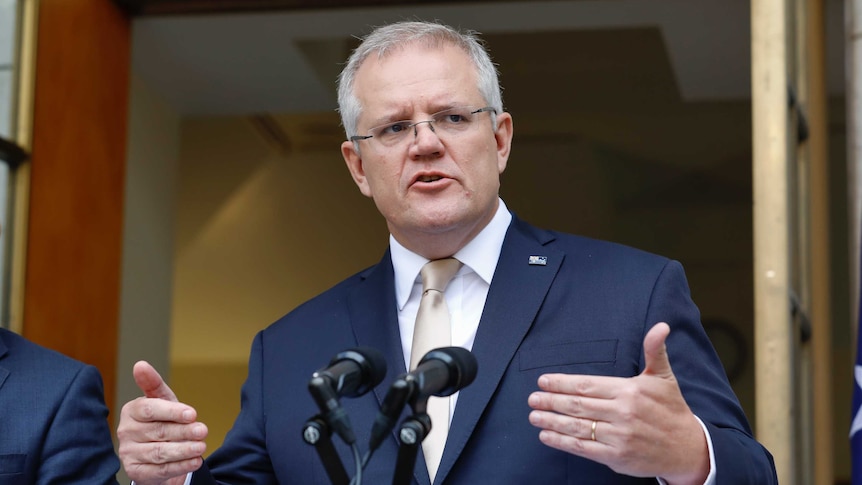 Scott Morrison, with an Australian flag pin on his suit, looks into the distance