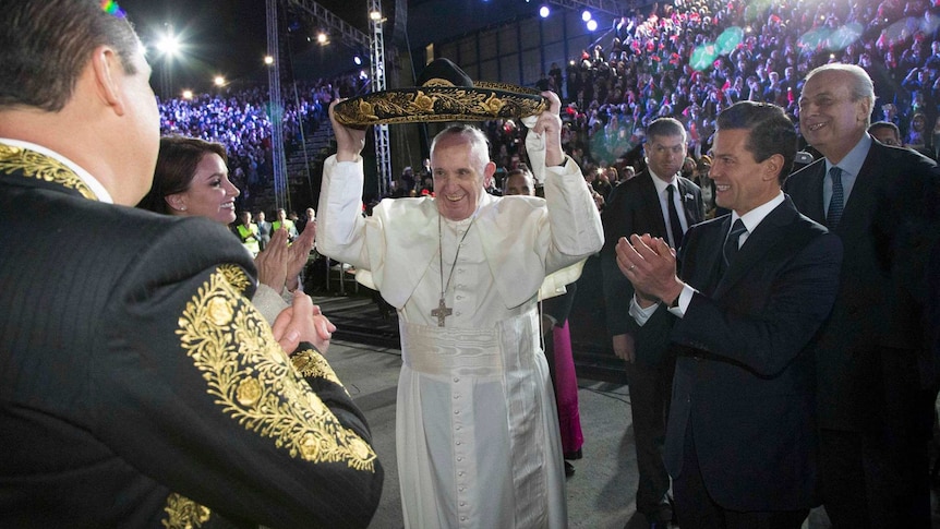 Pope Francis tries on a Mariachi hat while Mexico's president applauds.