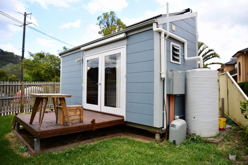 A blue coloured tiny home on a patch of grass