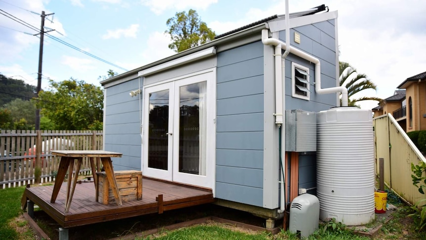 A blue coloured tiny home on a patch of grass