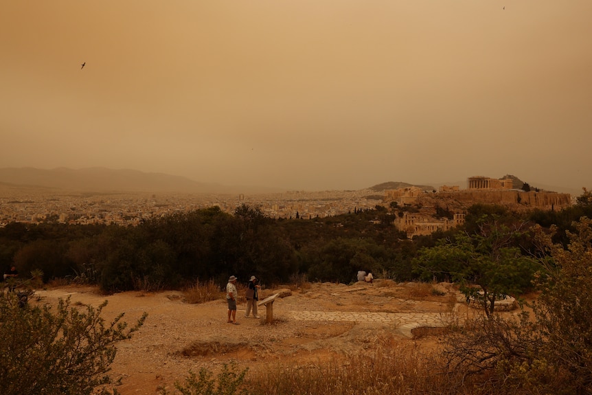 A wide photo of African dust covering the Acropolis and giving the atmosphere an orange hue.