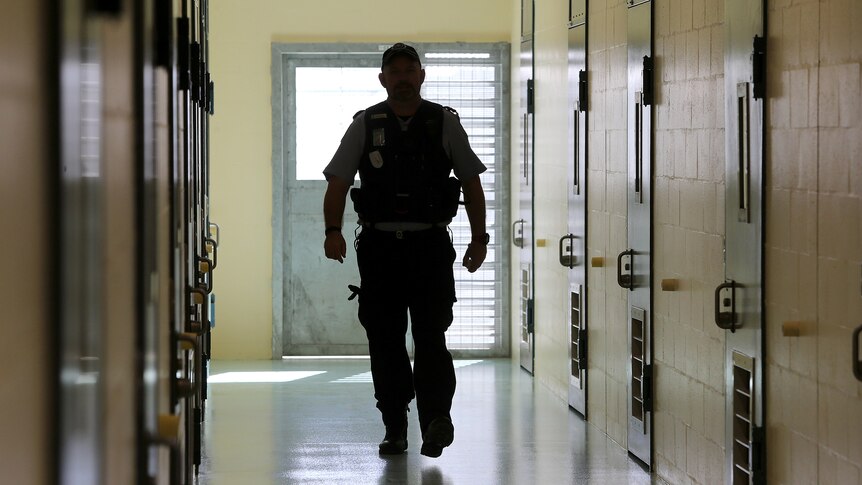 an officer of the law walking down a corridor in a prison