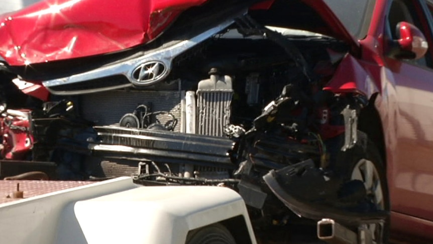 Close up of smashed car on tow truck being delivered to a vehicle auction yard.