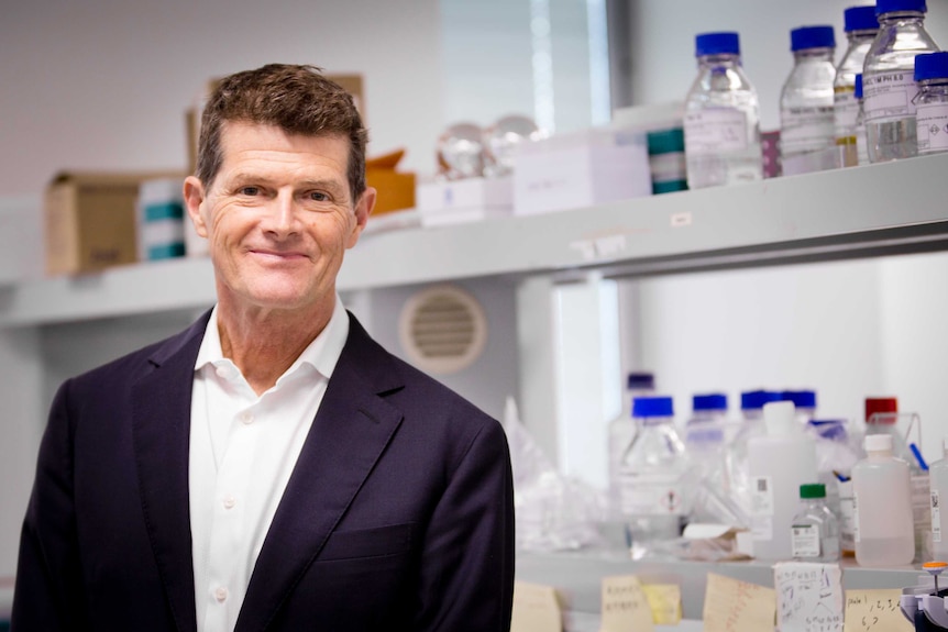 Lead scientist Professor Chris Goodnow stands in the laboratory at the Garvan Institute with bottles in the background.