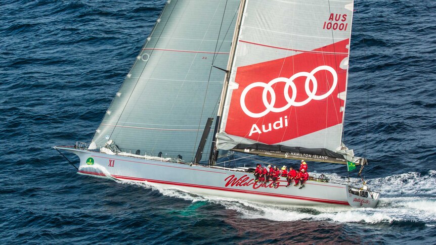 Wild Oats XI's crew sits on the side of the yacht