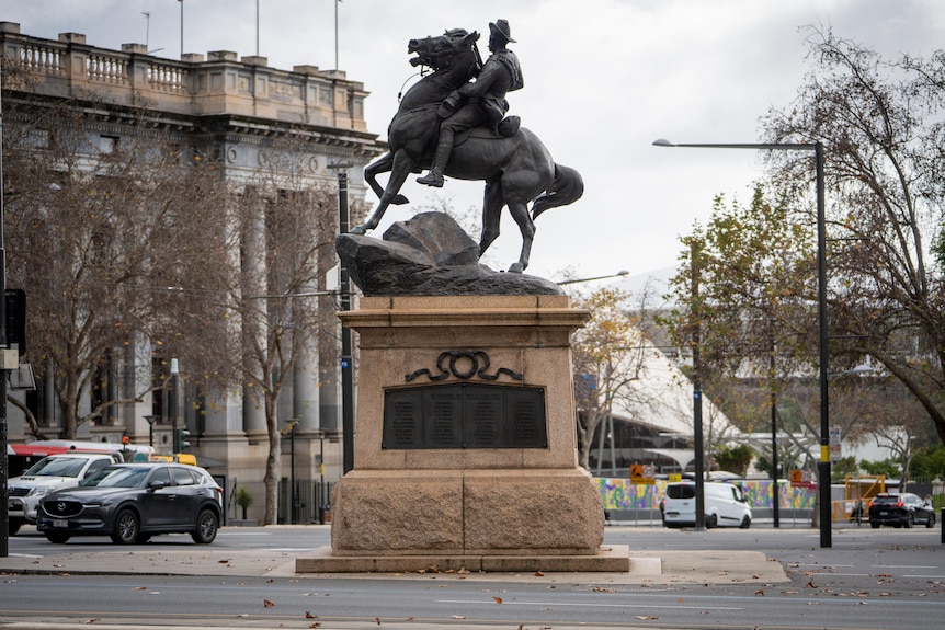 A statue of a soldier riding a horse on top of a monument with names listed