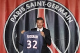 David Beckham poses with his Paris Saint-Germain shirt after signing for the French side.