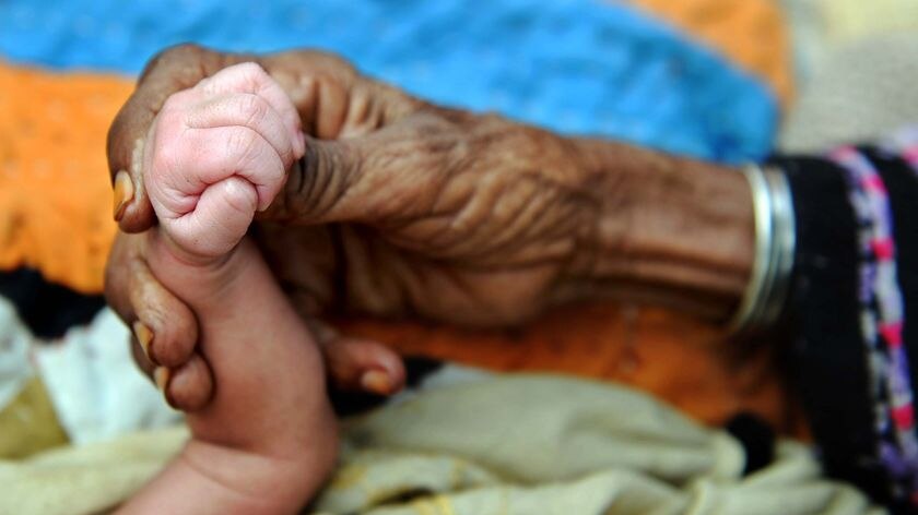 A Pakistani grandmother holds the hand of her three-day-old grandchild